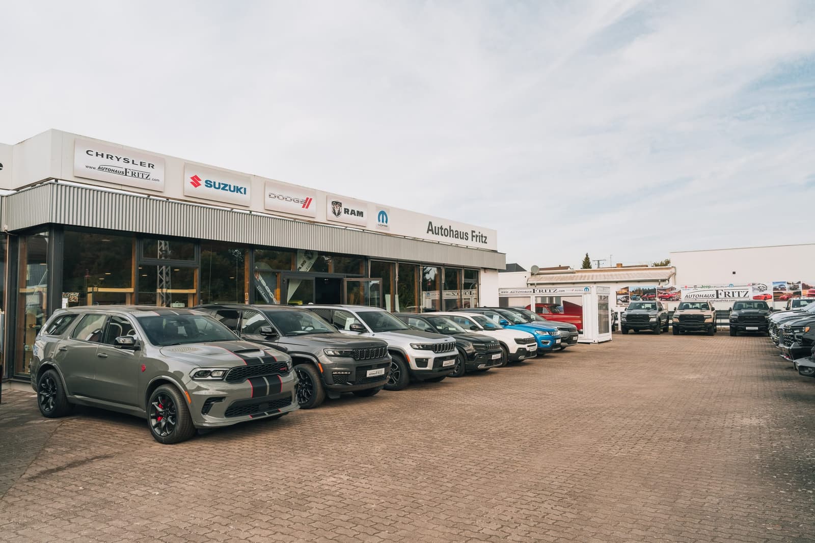 The Autohaus Fritz showroom building with brand signs on the facade, vehicles on the forecourt in front