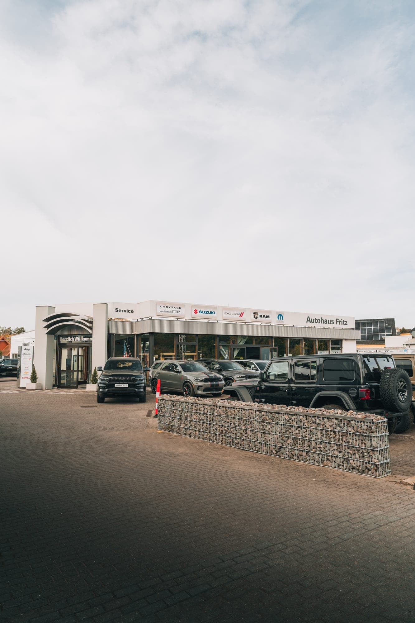Autohaus Fritz in Oppin seen from the entrance: the sales building with brand signs, vehicles on the forecourt in front of it