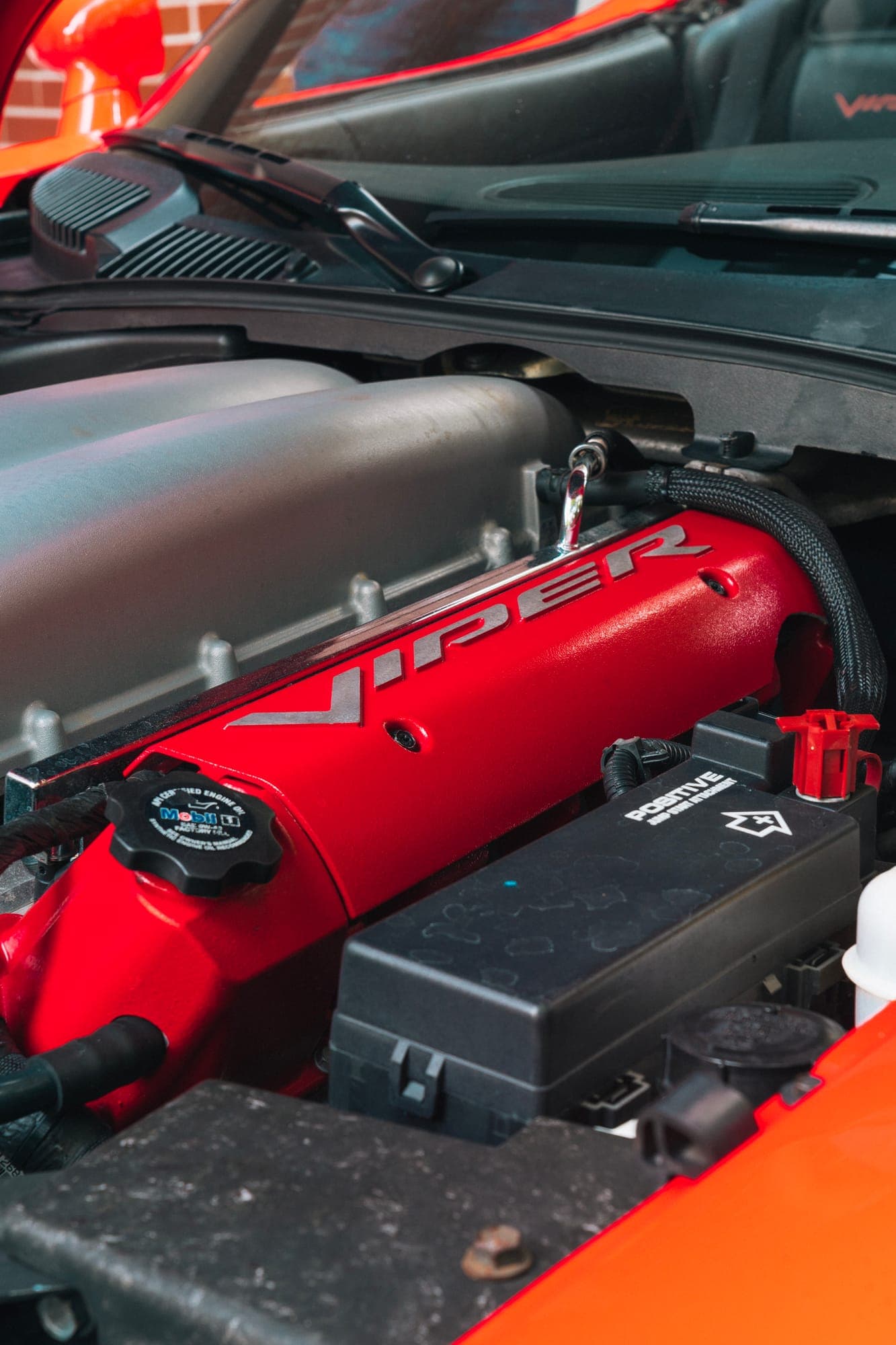 Open engine bay with a red cover and silver Viper lettering, next to it the black oil filler cap